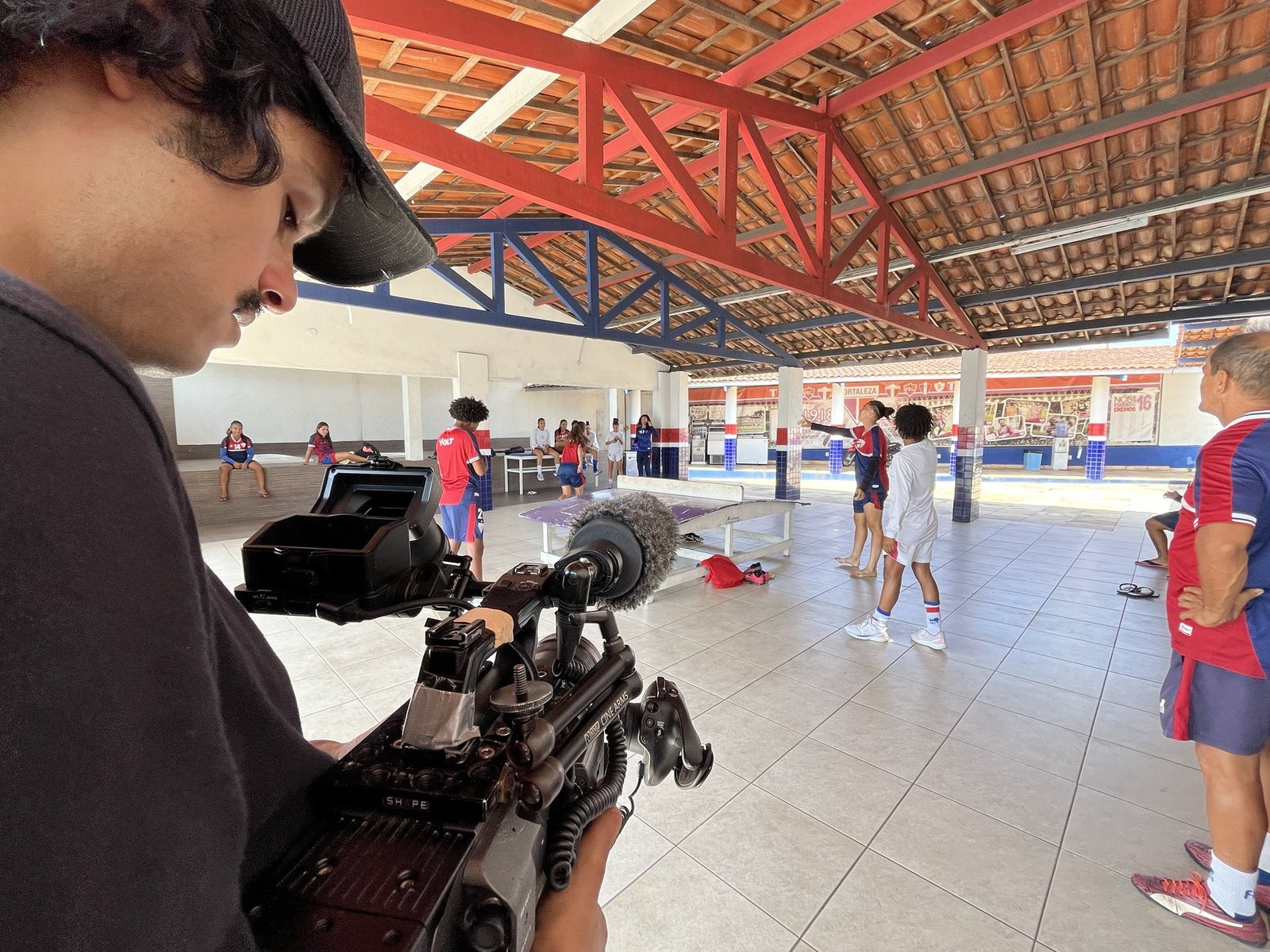 A equipe filma as jogadoras no Fortaleza Esporte Clube, com câmera e microfone em primeiro plano.